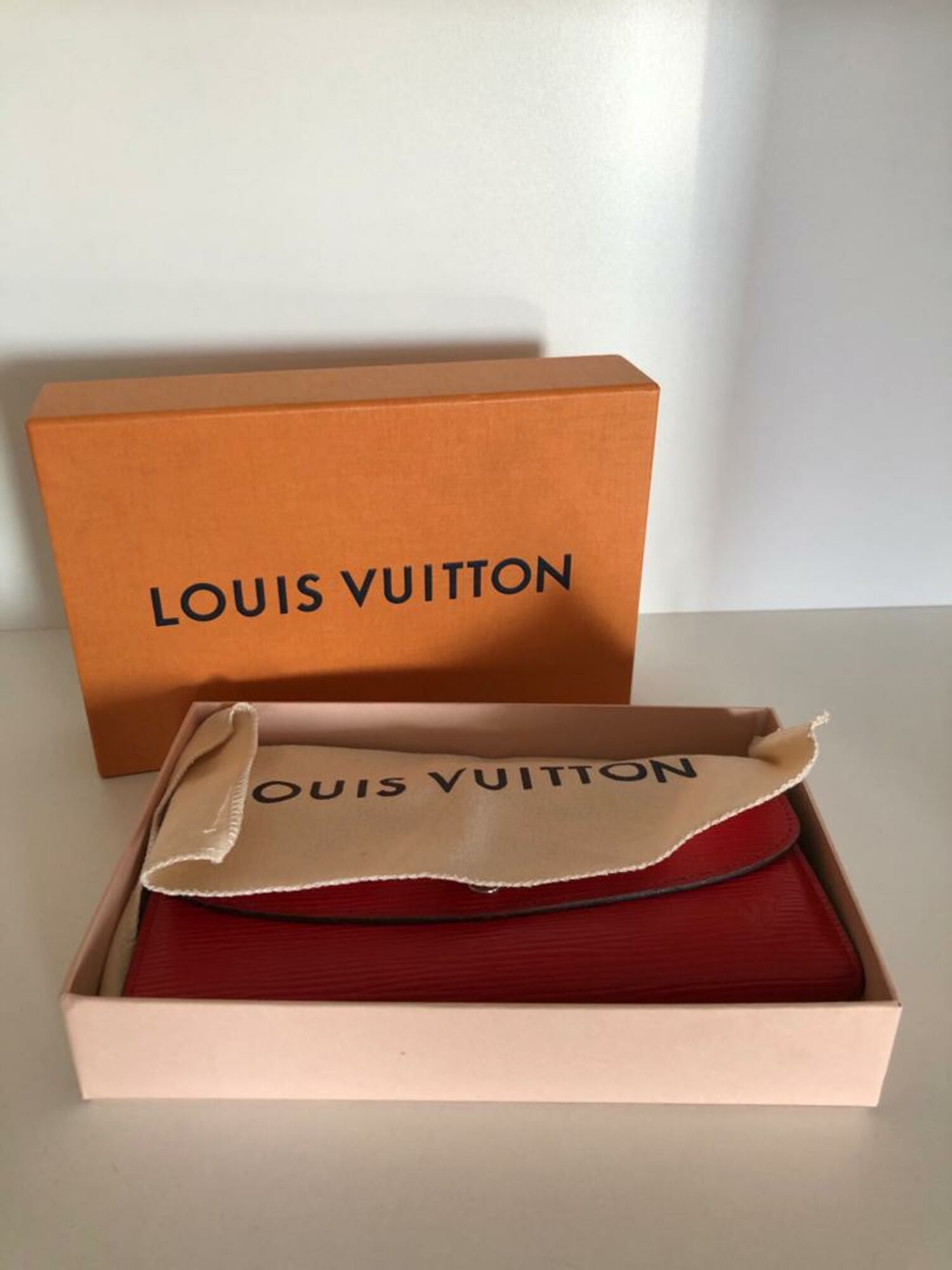 LOUIS VUITTON ELYSEE MONOGRAM WALLET with gold tone clasp at the front and  red partitioned leather interior with a central zippered pocket and twelve  card slot panels with dust bag box and
